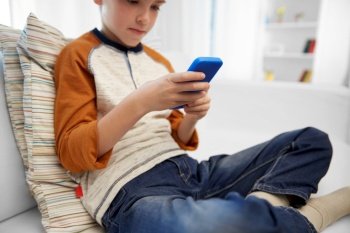 leisure, technology and childhood concept - close up of boy with smartphone at home. close up of boy with smartphone at home