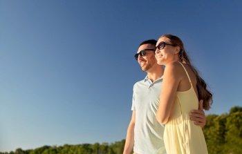 leisure, relationships and people concept - happy couple in sunglasses hugging outdoors in summer. happy couple hugging outdoors in summer