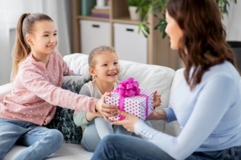 people, family and holidays concept - two daughters giving present to happy mother at home. daughters giving present to happy mother
