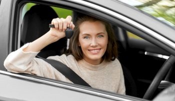 driving, safety and people concept - young woman or female driver sitting in car and showing key. woman or female driver with car key in city