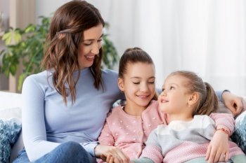 people, family and love concept - happy smiling mother with two daughters at home. happy smiling mother with two daughters at home
