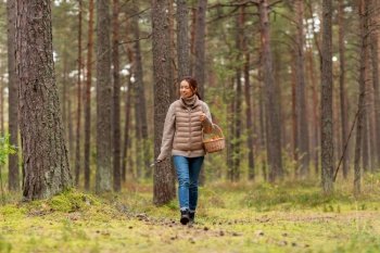 picking season, leisure and people concept - young asian woman with mushrooms in basket walking in autumn forest. young woman picking mushrooms in autumn forest