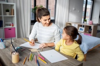 family, motherhood and leisure concept - mother spending time with her little daughter drawing with color pencils at home. mother with little daughter drawing at home