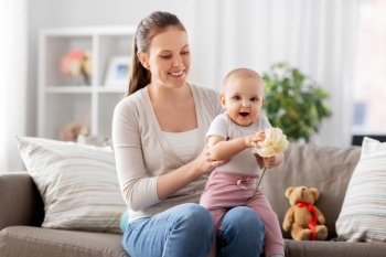family, motherhood and people concept - happy smiling mother and little baby daughter playing with flower at home. happy smiling mother with little baby at home