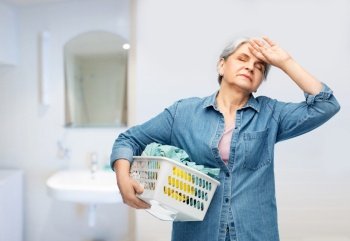 cleaning, wash and old people concept - tired senior woman in denim shirt with laundry basket over bathroom background. tired senior woman with laundry basket