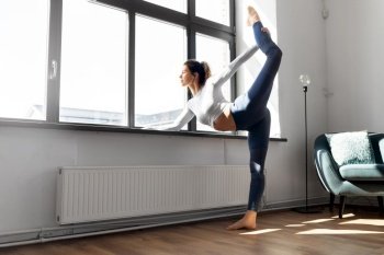 fitness, sport and healthy lifestyle concept - woman doing yoga exercise at window sill at studio. woman doing yoga exercise at window sill at studio