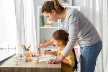 family, motherhood and leisure concept - mother spending time with her little daughter drawing picture with colors at home. mother with little daughter drawing at home