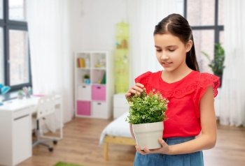 environment, nature and people concept - happy smiling girl holding flower in pot over kids room background. happy smiling girl holding flower in pot