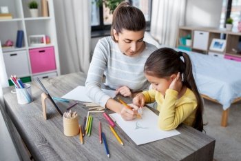 family, motherhood and leisure concept - mother spending time with her little daughter drawing with color pencils at home. mother with little daughter drawing at home