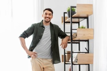 home improvement and decoration and people concept - happy smiling man standing at shelf at home. happy smiling man standing at shelf at home