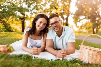 leisure, vacation and people concept - happy couple lying on picnic blanket at summer park. happy couple on picnic blanket at summer park