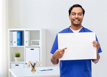healthcare, profession and medicine concept - happy smiling indian male doctor or nurse in blue uniform with board over medical office at hospital background. smiling male doctor or nurse with white board