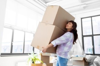moving, people and real estate concept - happy smiling asian woman holding big boxes with stuff at new home. happy woman holding boxes and moving to new home