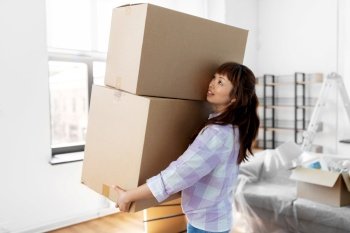 moving, people and real estate concept - happy smiling asian woman holding big boxes with stuff at new home. happy woman holding boxes and moving to new home