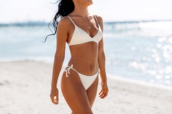 people, summer and swimwear concept - body of young woman in bikini swimsuit on beach. body of young woman in bikini swimsuit on beach