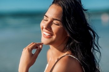 people, summer and swimwear concept - close up of happy smiling young woman on beach. close up of happy smiling young woman on beach
