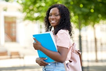 education, school and people concept - happy smiling african american student girl with notebooks in city. african student girl with notebooks in city
