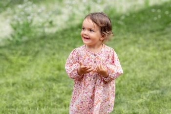 childhood, leisure and people concept - happy little baby girl in pink dress outdoors in summer. happy little baby girl outdoors in summer