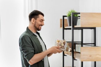 home improvement and decoration and people concept - woman placing seashells in vase to shelf. man decorating home with seashells in vase