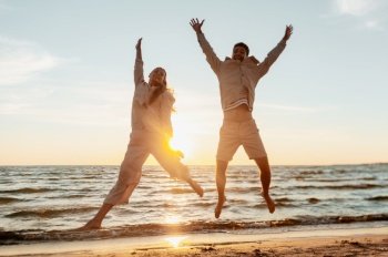leisure, relationships and people concept - happy couple jumping on summer beach. happy couple jumping on summer beach