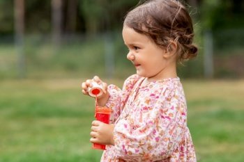 childhood, leisure and people concept - happy little baby girl with soap bubble blower in summer. happy baby girl with soap bubble blower in summer