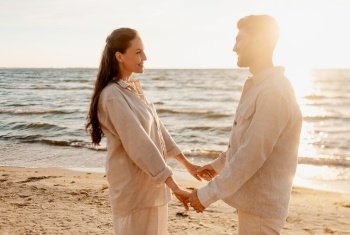 leisure, relationships and people concept - happy couple holding hands on summer beach. happy couple holding hands on summer beach