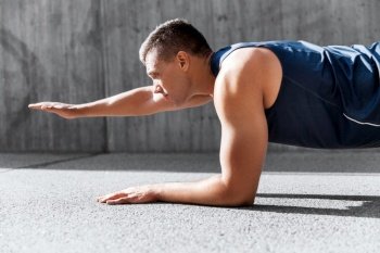 fitness, sport and training concept - young man doing plank on city street. young man doing plank on city street