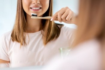 dental care, hygiene and people concept - happy smiling teenage girl with toothbrush brushing teeth at bathroom. teenage girl with toothbrush brushing teeth