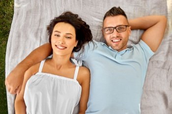 leisure, vacation and people concept - happy couple lying on picnic blanket. happy couple on picnic blanket