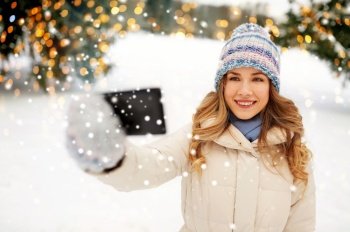 people, season and leisure concept - happy smiling woman taking selfie by smartphone in winter with festive lights on background. woman taking selfie by smartphone in winter