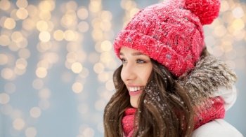 people, season and christmas concept - portrait of happy smiling teenage girl or young woman in winter over festive lights background. smiling teenage girl outdoors in winter