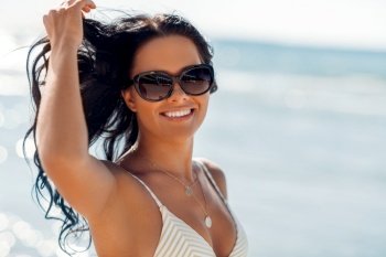 people, summer and swimwear concept - happy smiling young woman in bikini swimsuit on beach. smiling young woman in bikini swimsuit on beach