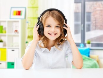 technology and music concept - happy smiling girl with headphones over home room background. happy smiling girl with headphones at home