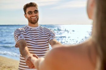 leisure, relationships and people concept - happy couple in sunglasses having fun on summer beach. happy couple having fun on summer beach