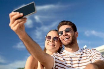 technology, leisure and people concept - happy couple taking selfie by smartphone outdoors in summer. happy couple taking selfie by smartphone outdoors