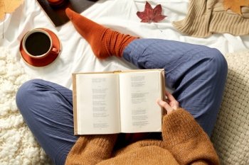people, season and leisure concept - young woman reading book at home in autumn. young woman reading book at home in autumn