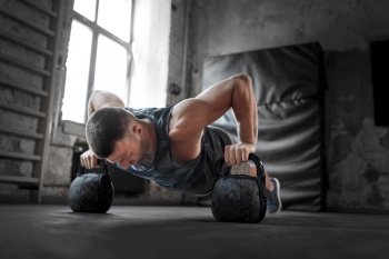 sport, bodybuilding, fitness and people concept - young man doing kettlebell push-ups in gym. young man doing kettlebell push-ups in gym