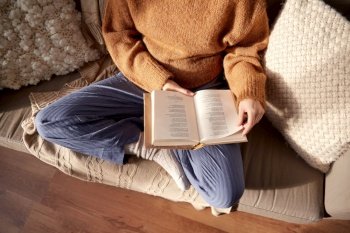 people, season and leisure concept - close up of woman in warm sweater reading book at home. woman in warm sweater reading book at home