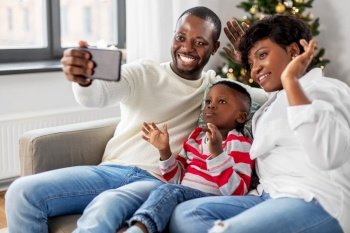 family, winter holidays and people concept - happy african american mother, father and little son taking selfie at home on christmas. african family taking selfie on christmas at home
