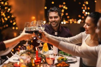 holidays, party and celebration concept - multiethnic group of happy friends having christmas dinner at home and drinking wine. happy friends drinking wine at christmas party