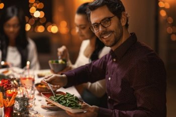 holidays, party and celebration concept - happy man with friends having christmas dinner at home. happy man with friends having christmas dinner