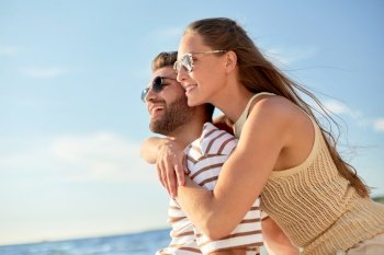 leisure, relationships and people concept - happy couple in sunglasses hugging on summer beach. happy couple hugging on summer beach