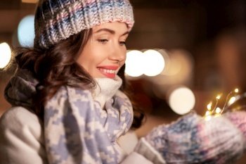 winter holidays and people concept - portrait of happy smiling young woman in christmas garland lights. portrait of happy young woman in christmas lights