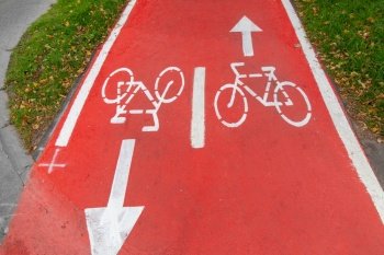 traffic, road marking and city concept - close up of red bike lane with signs of bicycles and two way arrows on street. bike lane or red road with signs of bicycles