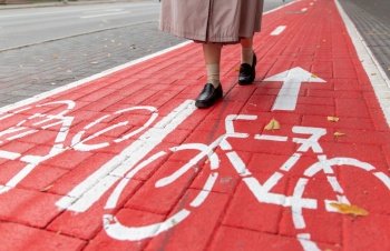 city and traffic concept - close up of woman’s feet walking along separate bike lane or red road with signs only for bicycles on street. feet walking along bike lane or road for bicycles