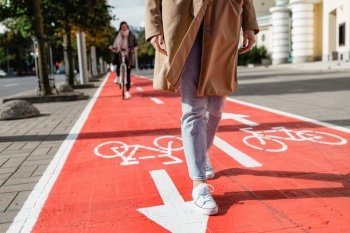 people, city and traffic concept - close up of woman’s feet walking along separate bike lane or red road with signs only for bicycles on street. feet walking along bike lane or road for bicycles