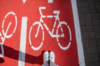 city and traffic concept - feet in gumshoes on separate bike lane or red road with signs only for bicycles on street. feet in gumshoes on bike lane or road for bicycles