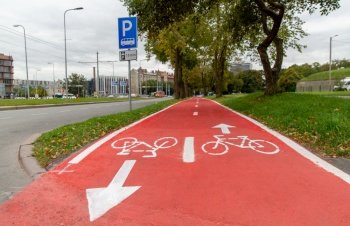 traffic, road marking and city concept - red bike lane with signs of bicycles and two way arrows on street in tallinn. bike lane or red road with signs of bicycles