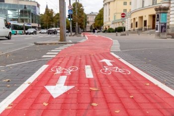 traffic, marking and city concept - red bike lane or road crossing with signs of bicycles and two way arrows on street in tallinn. bike lane or red road with signs of bicycles