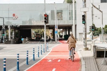 traffic, city transport and people concept - woman cycling along red bike lane with signs of bicycles and two way arrows on street in tallinn, estonia. woman cycling along red bike lane road in city